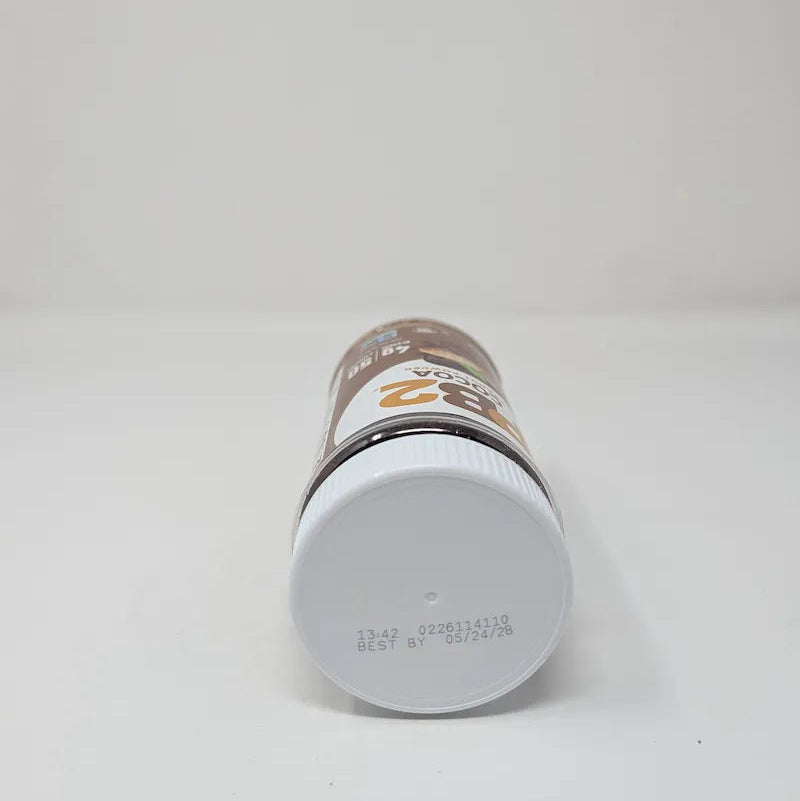 Top view of jar of PB2 Cocoa Peanut Powder on a plain white background. The product is in a clear plastic jar showing the brown powder inside, with a white ribbed lid and a brown and white label featuring the PB2 logo and cocoa bean illustrations.