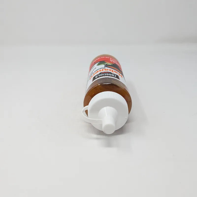 Top view of a bottle of Zaaschila Habanero Homestyle Hot Sauce on a plain white background. The bottle has a white cap with a built-in loop, and features a label with red, white, and black colors showing peppers and a bowl of sauce.