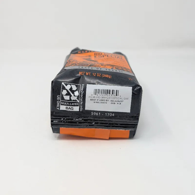 Bottom view of a 12 ounce bag of Cafe Ole by H-E-B Rio Grande Especial ground coffee featuring an orange and black color scheme on a plain white background.