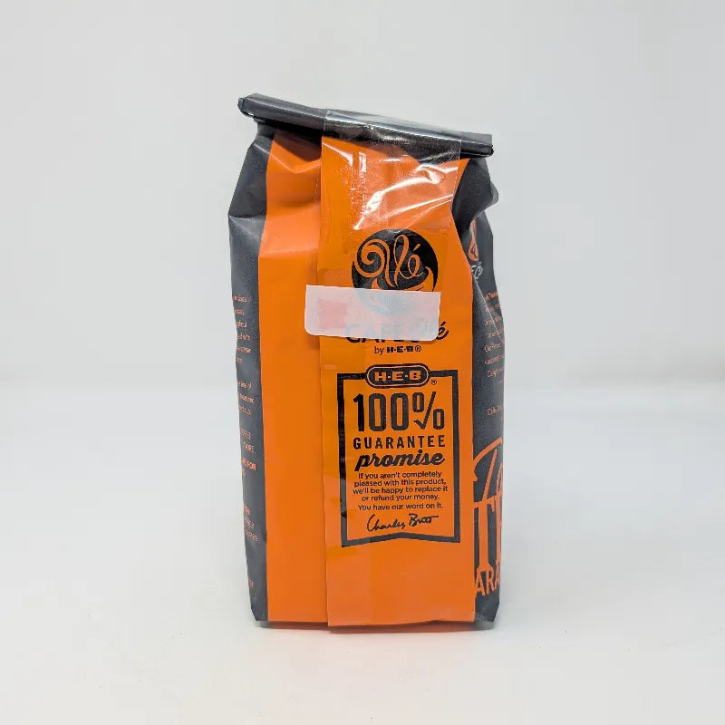 Rear view of a 12 ounce bag of Cafe Ole by H-E-B Rio Grande Especial ground coffee featuring an orange and black color scheme on a plain white background.