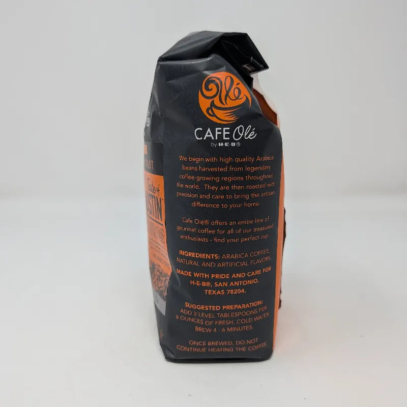 Side view of A 12 ounce bag of Cafe Olé by H-E-B Ground Medium Roast Taste of Austin coffee, featuring a black and orange package design with ingredients list.