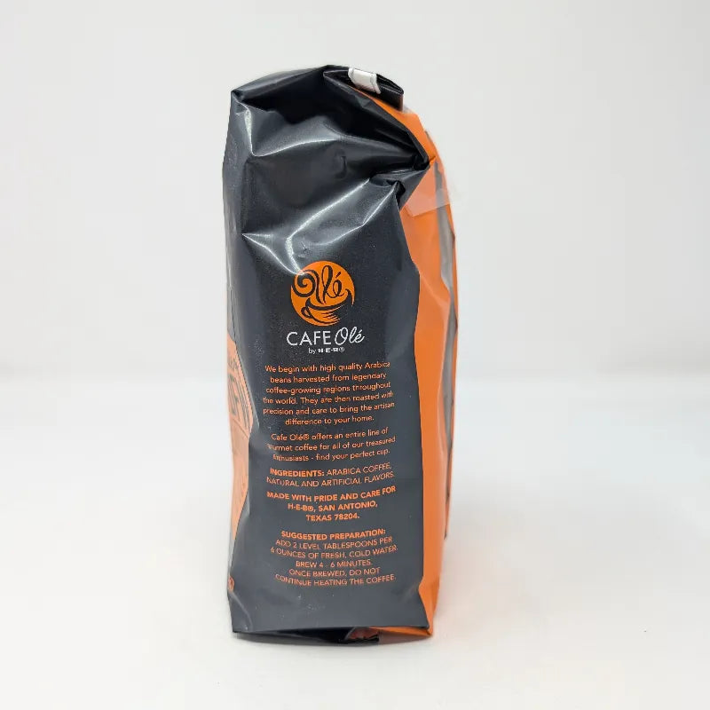 Side view of a 12 ounce bag of Cafe Ole by H-E-B Taste of DFW Medium Roast Ground Coffee featuring an orange and black color scheme on a plain white background. Includes ingredients list.