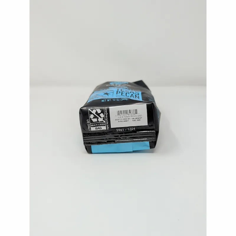 Bottom view of a 12 oz bag of Cafe Olé Texas Pecan ground coffee, medium roast, in a black bag with a blue label on a white background.