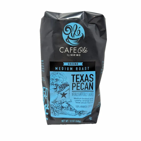 Front view of a 12 oz bag of Cafe Olé Texas Pecan ground coffee, medium roast, in a black bag with a blue label on a white background.