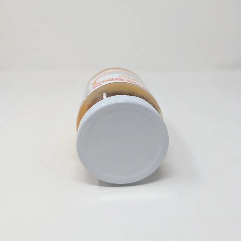 Top view of a jar of Hell on the Red Cheese Dip with a white label featuring yellow text and containing yellow queso on a white background.