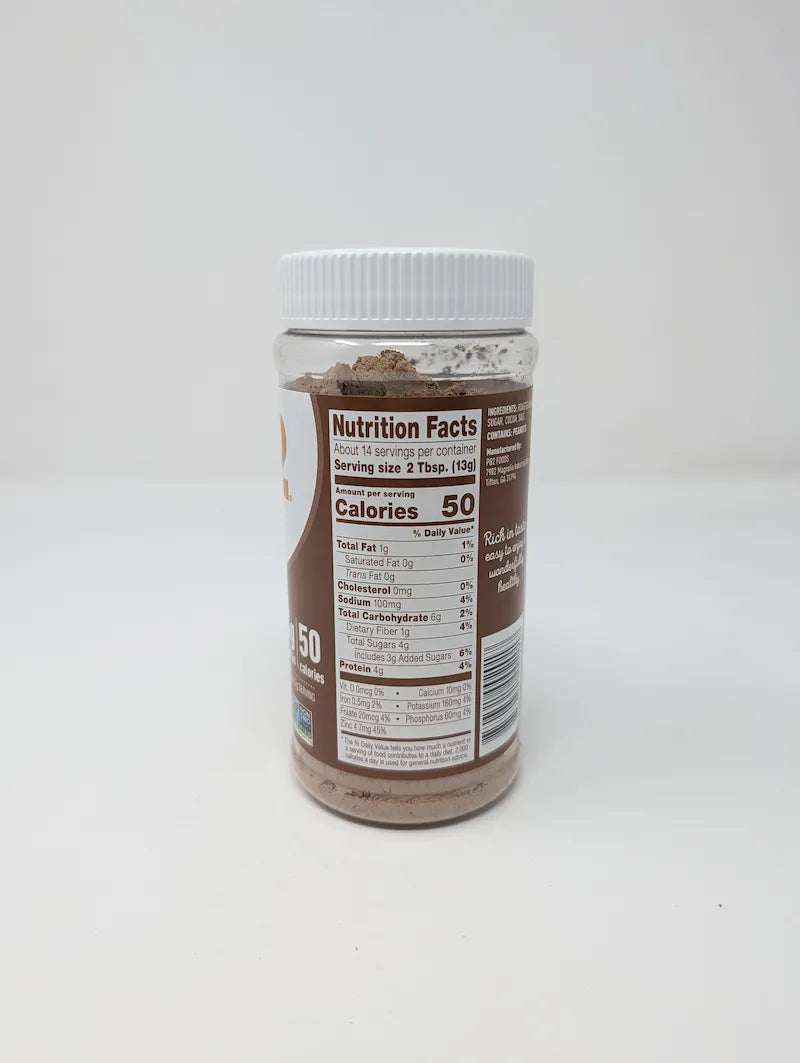 Side view of jar of PB2 Cocoa Peanut Powder including Nutrition Facts on a plain white background. The product is in a clear plastic jar showing the brown powder inside, with a white ribbed lid and a brown and white label featuring the PB2 logo and cocoa bean illustrations.
