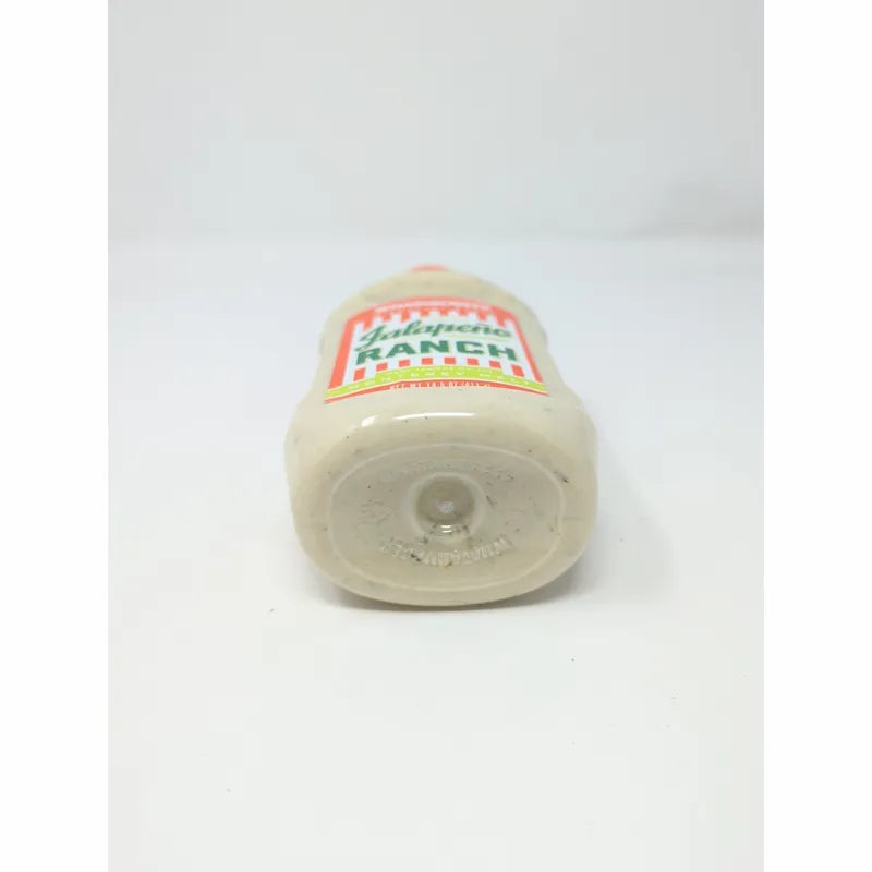 Bottom view of a  bottle of Whataburger Signature Sauce with an orange cap and a white sauce inside.